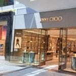 Storefront of Jimmy Choo with people inside, featuring glass doors and luxury displays.