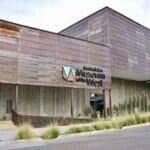 Exterior view of Scottsdale's Museum of the West, featuring a modern, wood-paneled architecture with signage and surrounding plants.